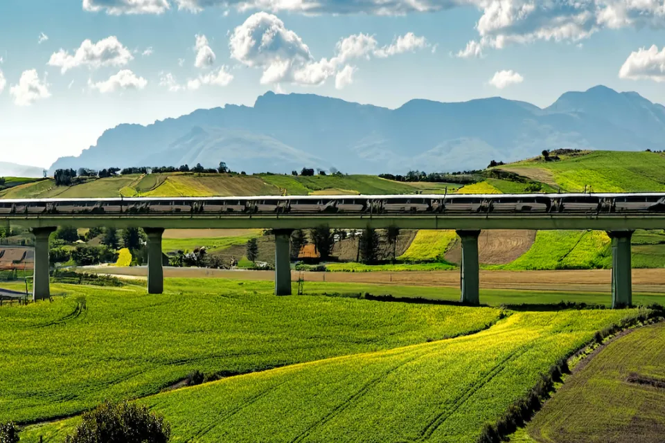 AI-generated image of high-speed rail trail in elevated track in green hilly farmland.